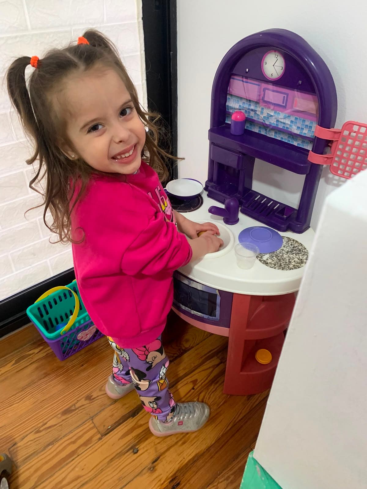 Nena sonriendo mientras juega en una cocinita de juguete.