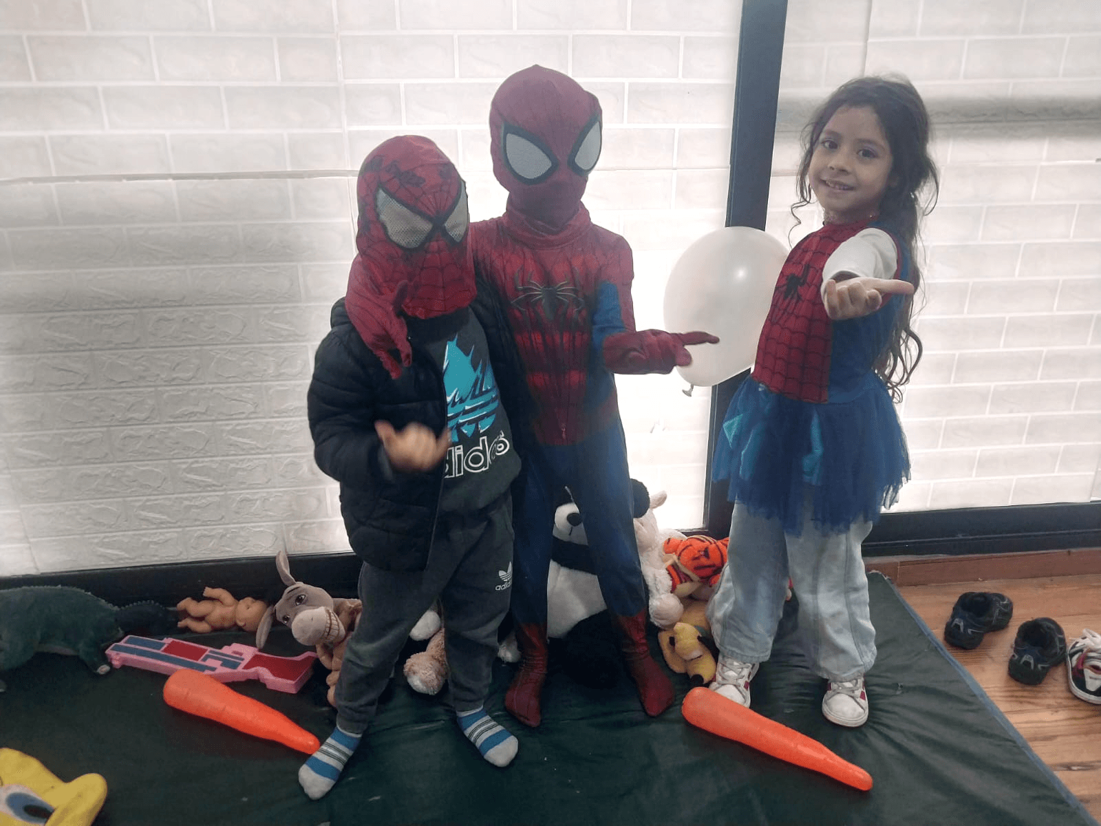 Tres niños disfrazados de Spider-Man posando con un globo.